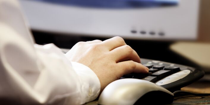 Großaufnahme einer Hand vor einer Computertastatur