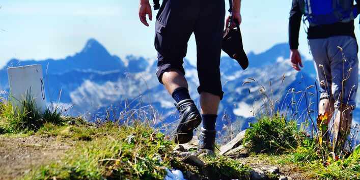 Beine eines Wanderers vor Hochgebirgskulisse.
