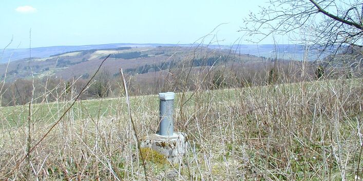 Grundwassermessstelle vor Landschaft.