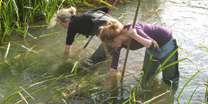 two women are fishing in the water to take some samples