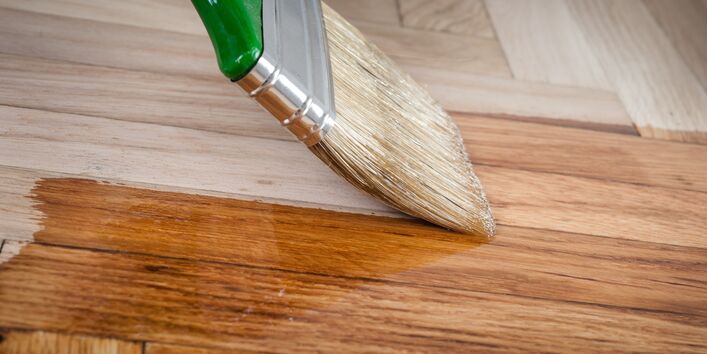 Pinsel lackiert ein Holz mit Klarlack.