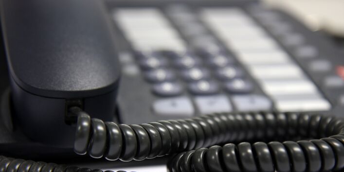 Nahaufnahme von einem schwarzen Telefonhörer mit Schnur