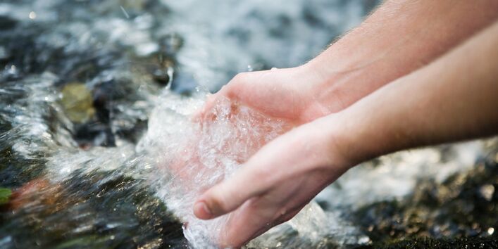 Klares Wasser fließt durch zwei Hände.