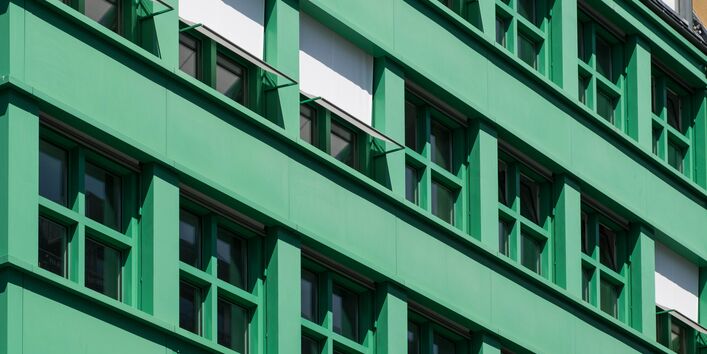 Eine Hausfassade mit Fenstern, die beschattet werden.