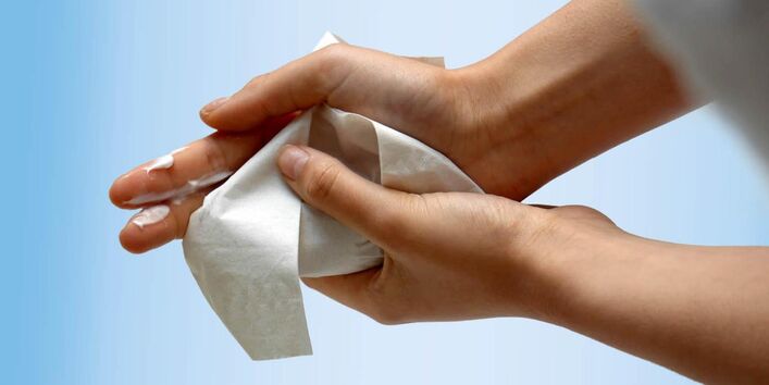 Photo showing hands with white cream, which is wiped off with a paper towel.
