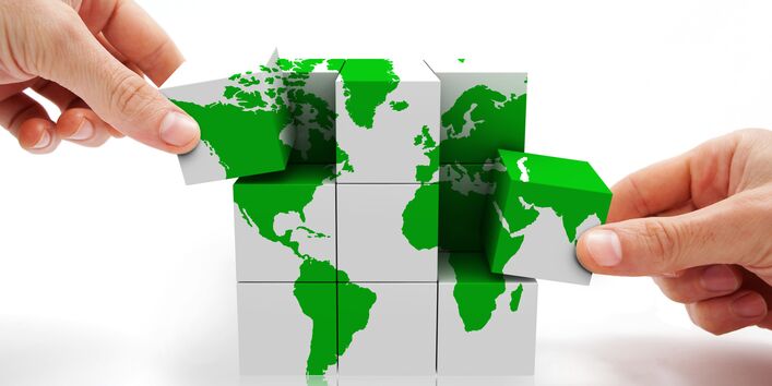 Zwei Hände mit Würfeln, die die Weltkarte abbilden.