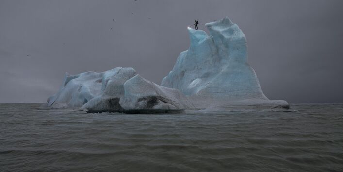 Eisberg im Meer auf dem eine Schattenfigut steht
