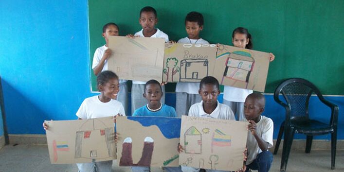 Kinder halten ihre Zeichnungen in die Kamera und strahlen