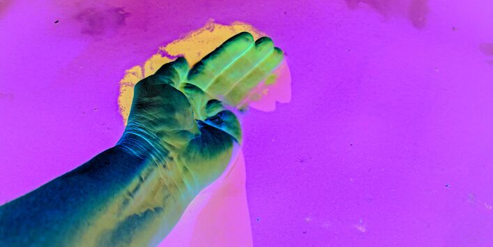 The picture shows the palm of a hand stroking the surface of a water body.