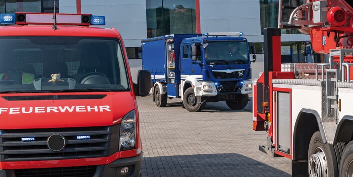 Das Bild zeigt zwei Einsatzfahrzeuge mit angeschaltetem Blaulicht, ein rotes der Feuerwehr und ein blaues des Technischen Hilfswerks. Beide Fahrzeuge sind nur in Teilen zu sehen.