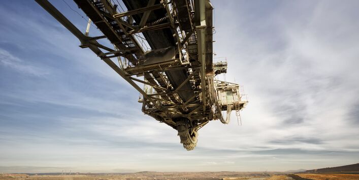Stillstehender Schauffelradbagger auf einem Kohletagebau, man sieht bewölkten Himmel und den Tagebau, bei dem Kohle abgebaut wird