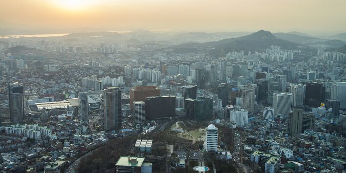 Blick über eine Großstadt, über der eine Smog-Wolke hängt; die Wolke verdecken fast die Sonne 