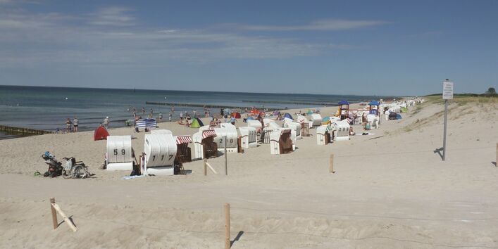 Das Bild zeigt einen Ostseestrand mit zahlreichen Strandkörben und dem Meer bei strahlendem Wetter.