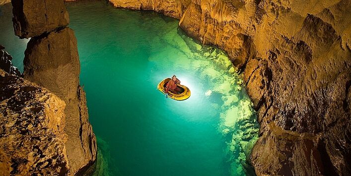 Ein Foto in der Blauhöhle. Zu sehen Grundwasser und eine Person in einem Boot.