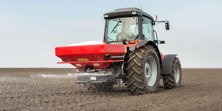 Ein Feld mit einem Dünger-Fahrzeug, um das Feld zu düngen 