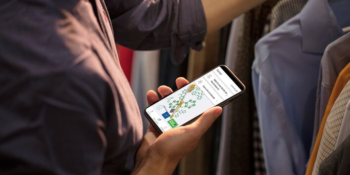 Eine Person mit einem Handy in der Hand. Zu sehen ist die App Scan4Chem auf dem Screen, mit der Barcodes gescannt werden können. 