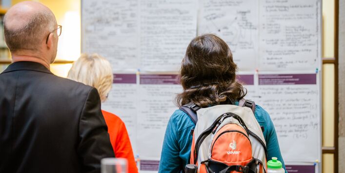 Teilnehmende stehen vor einer Stellewand, auf der die Arbeitsergebnisse auf Ergebnisbögen von den Teilnehmenden mit Fokus Forstwirtschaft skizziert haben.