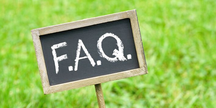 Kreidetafel mit Aufschrift vor einer grünen Wiese.