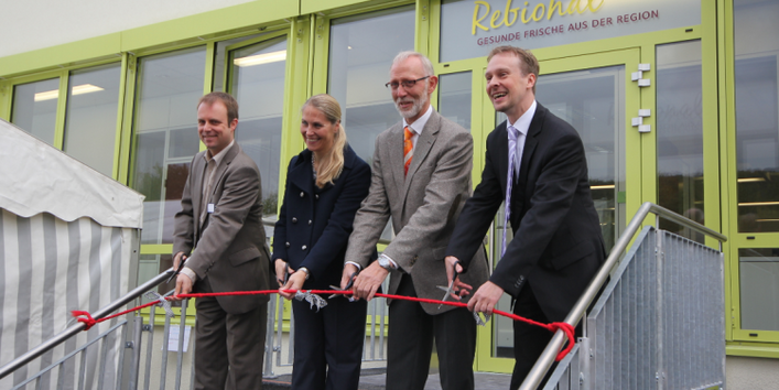 Zur Eröffnung der Großküche durchschneiden vier Personen ein rotes Band.