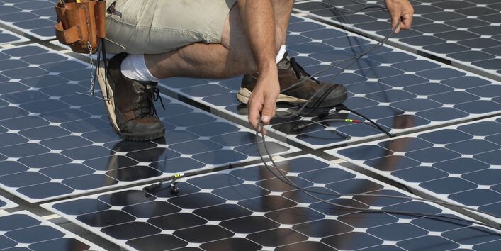 Ein Mann hockt auf einer photovoltaischen Anlage