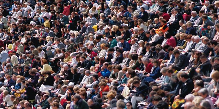Viele Menschen sitzen nebeneinander und schauen in die selbe Richtung