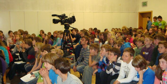 Ein gefüllter Saal mit Schulkindern.