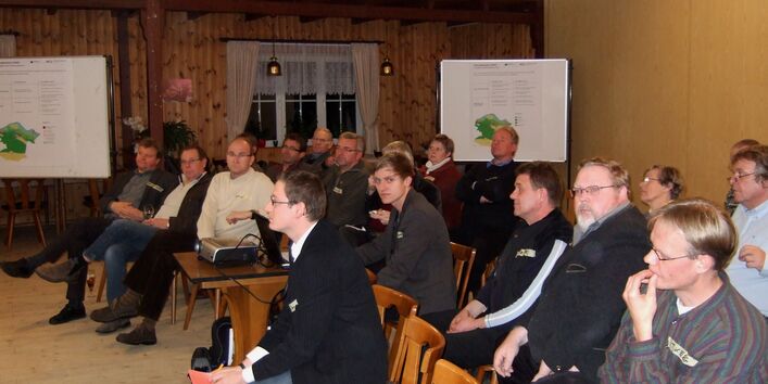 Viele Menschen sitzen in einem Saal, um den Leitbildentwurf zu hören.