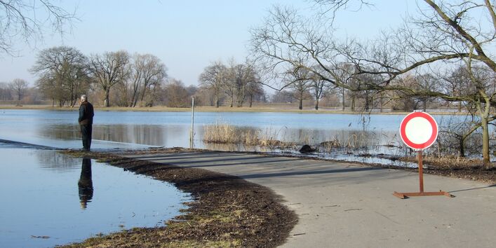 Ein Mann steht auf einem Betonweg. Das Wasser der Elbe reicht beinah bis zu seinen Füßen.