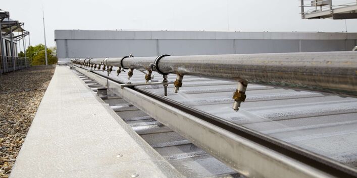 Dach wird über Rohrleitung mit Düsen mit Wasser besprenkelt.
