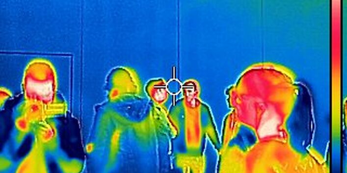 Wärmebildaufnahme aus den messtechnischen Übungen. Personen sind durch Farben als warm zu erkennen, während die Wand im Hintergrund kalt ist.