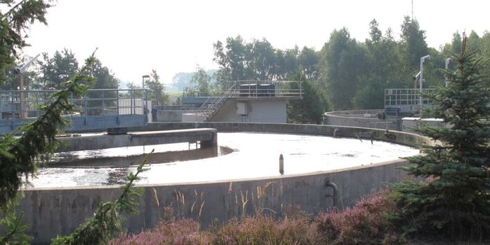 In einem großen runden Behälter aus Beton befindet sich Wasser. Der Behälter steht in der freien Natur.