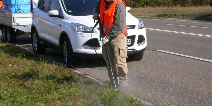 Ein Mann versprüht am grünen Straßenrand kochendes Wasser gegen den Wuchs der Hohen Ambrosie nach der Wave Methode