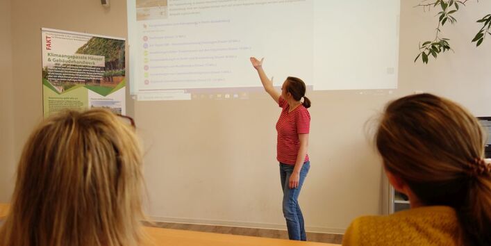 Auf einer an die Wand geworfenen Projektion vermittelt eine Person in einer Unterrichtssituation Inhalte.