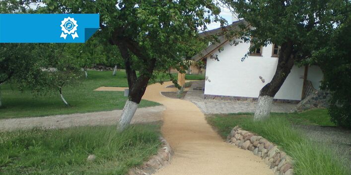 Ein Foto einer nicht-asphaltierten Wegkreuzung vor einem Haus.