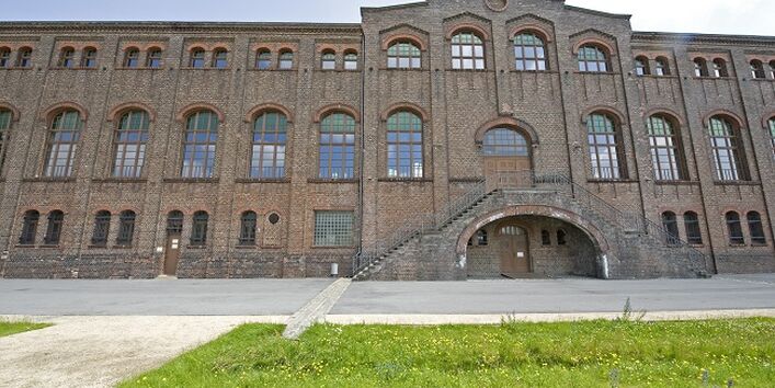 Ansicht eines Gebäudes aus Backstein mit Rasenstreifen im Vordergrund: Das Industriedenkmal Maschinenhalle Zweckel.
