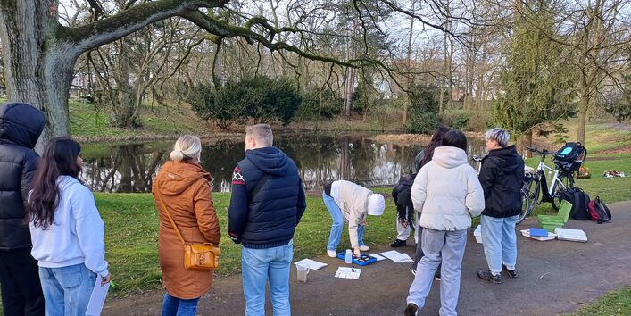 Jugendliche ermitteln Daten im Rahmen des Citizen Science Programms KlimPark an einem Gewässer im Park.