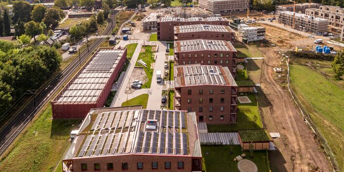 Der Blick von oben auf die PVT-Module als Ergänzung der Geothermie-Wärmepumpe und für Mieterstrom unter hellen, bewölkten Himmel