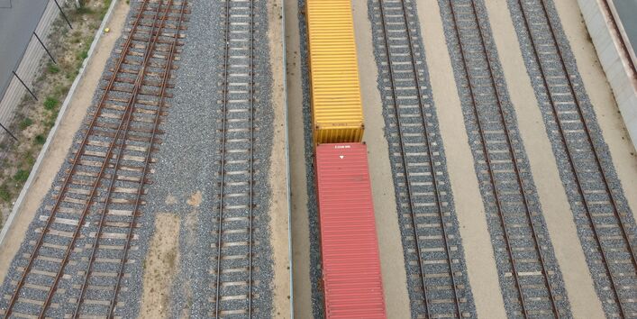Schieneninfrastruktur im Osnabrücker Hafen. Ein Zug mit gelb und roten Waggons ist von oben sichtbar.
