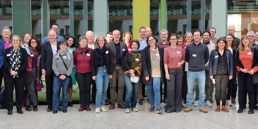 36 Frauen und Männer mit Namensschildern haben sich im begrünten Innenhof des UBA Dessau zum Gruppenfoto aufgestellt