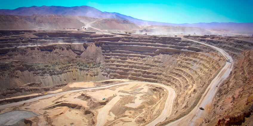 in einer bergigen, trockenen Landschaft klafft ein riesiges tiefes Loch mit terrassenförmigen Plateaus in der Erde
