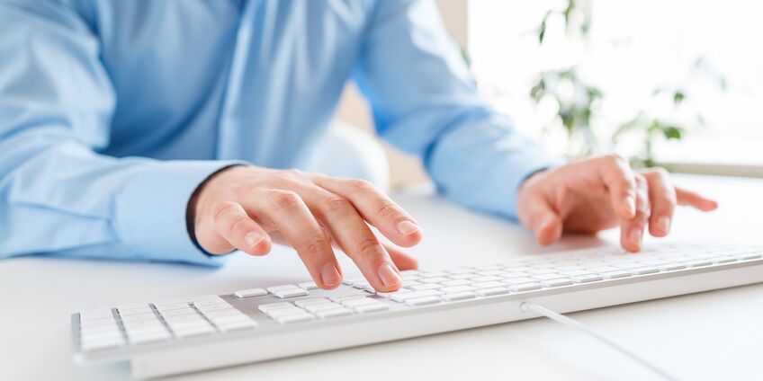 Mann tippt auf einer Computertatstatur