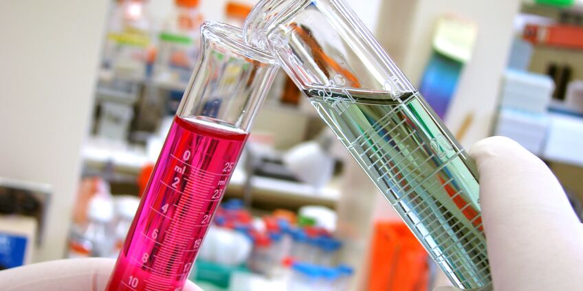 Inhalt von zwei Reagenzgläsern wird in einem Labor zusammengeschüttet