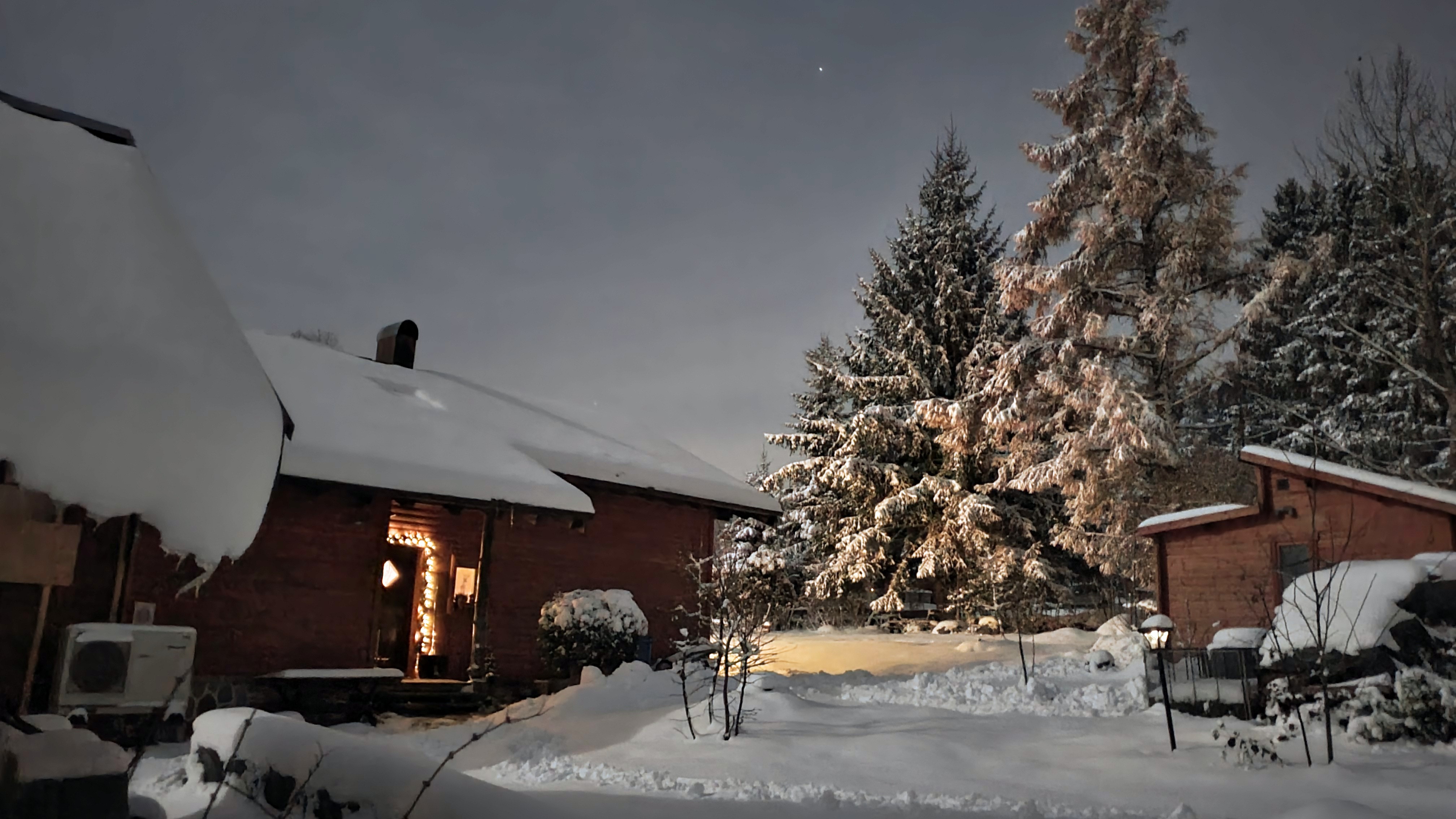 Eine Wärmepumpe vor Holzhaus im Schnee.