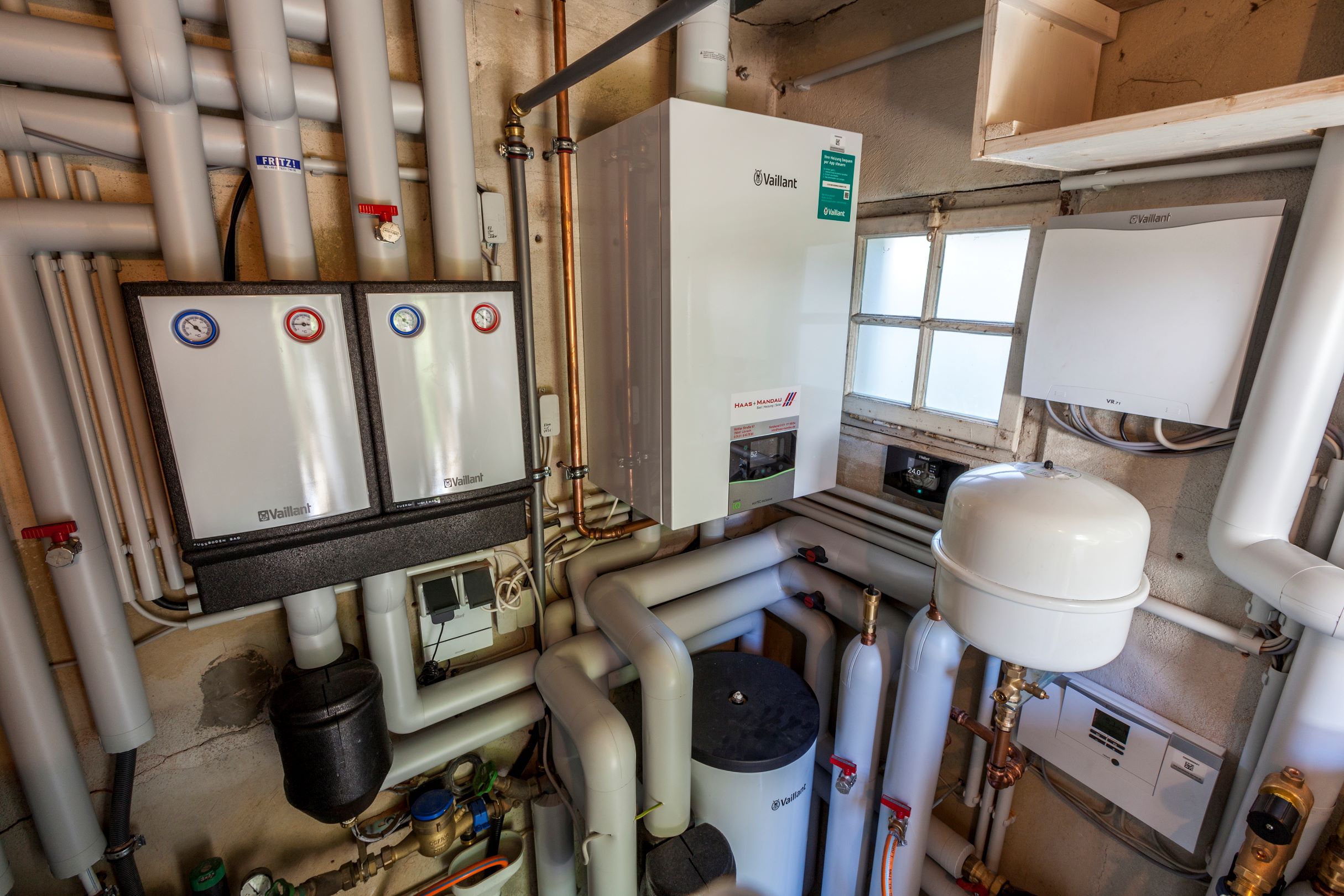 Heizungsraum Innenansicht mit Hydraulikstationen, Spitzenlast-Gastherme, Speicher und isolierten Rohren