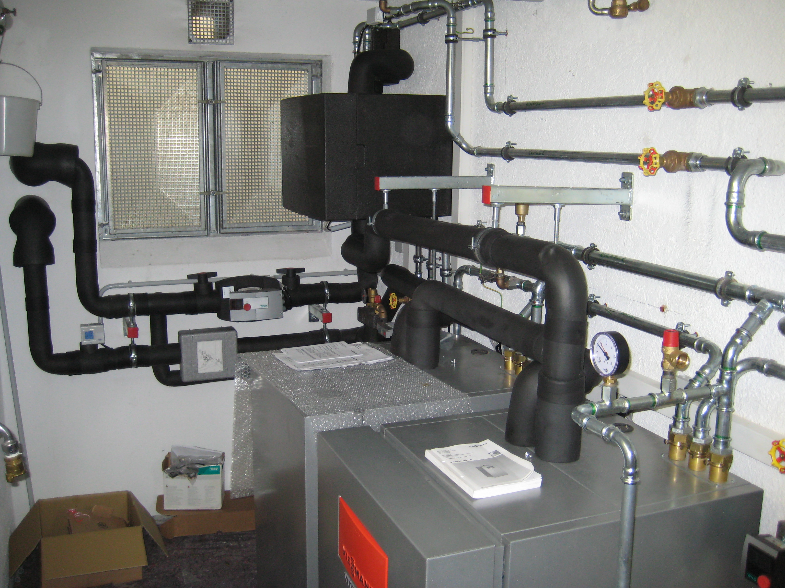 Zwei Wärmepumpen im Heizungskeller, Verrohrungen an der Wand.
