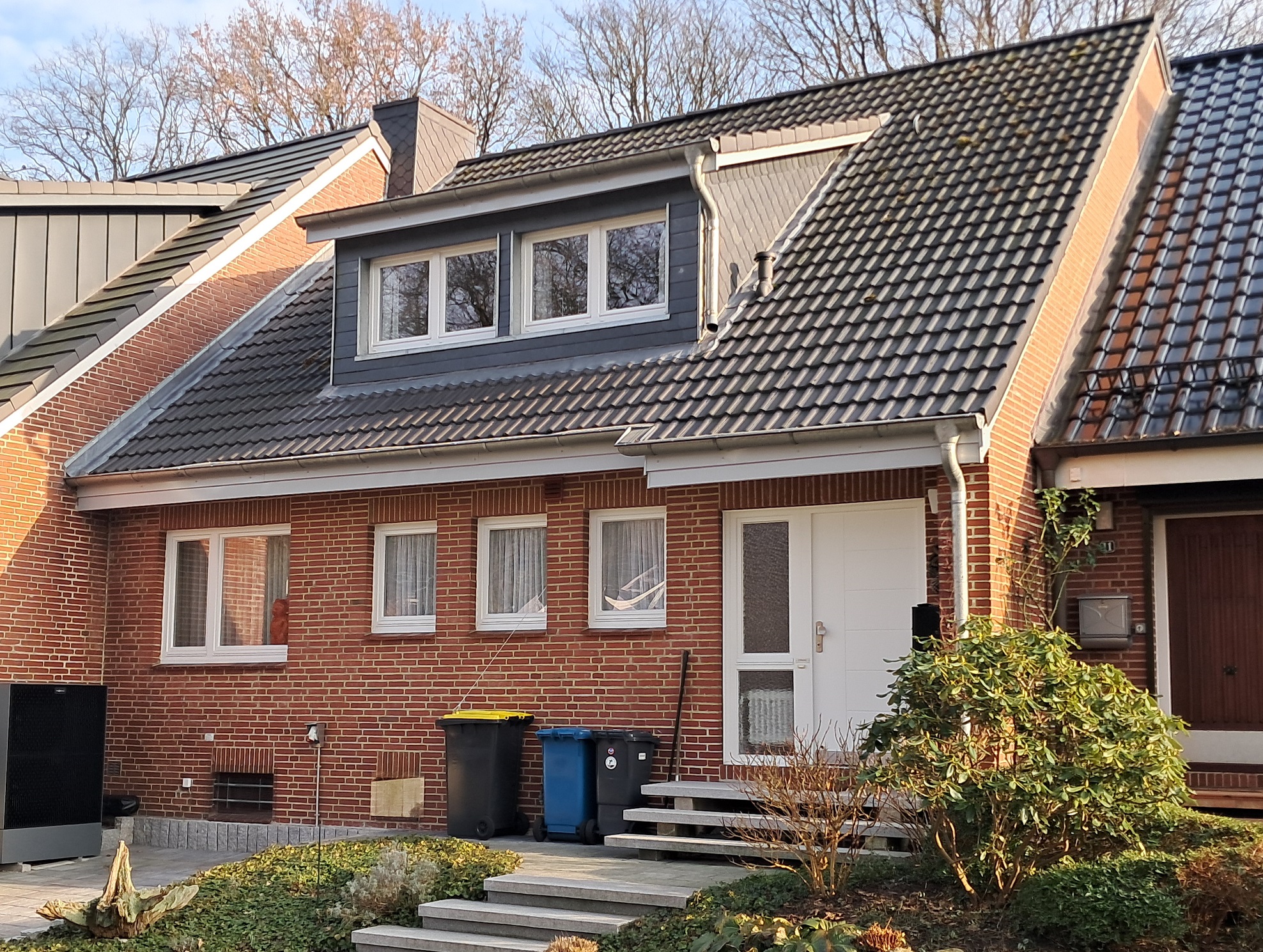 Straßenansicht des geklinkerten Reihenmittelhauses mit Dachgaube auf dem schwarzen Dach